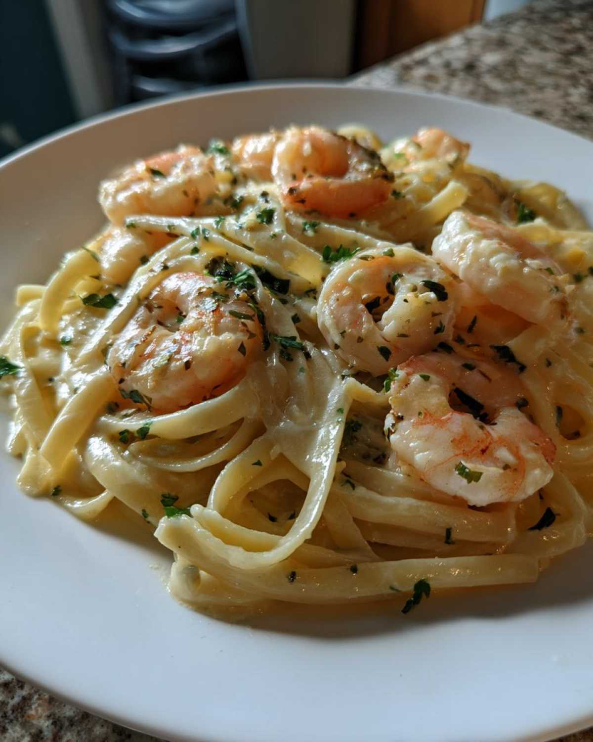 Close-up of fettuccine pasta coated in a creamy sauce, topped with seasoned shrimp and fresh parsley for Creamy Lemon Shrimp Pasta.