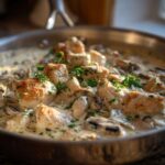 Close-up of seared chicken pieces and mushrooms simmering in a rich sauce in the Creamy Mushroom Alfredo Chicken Skillet.
