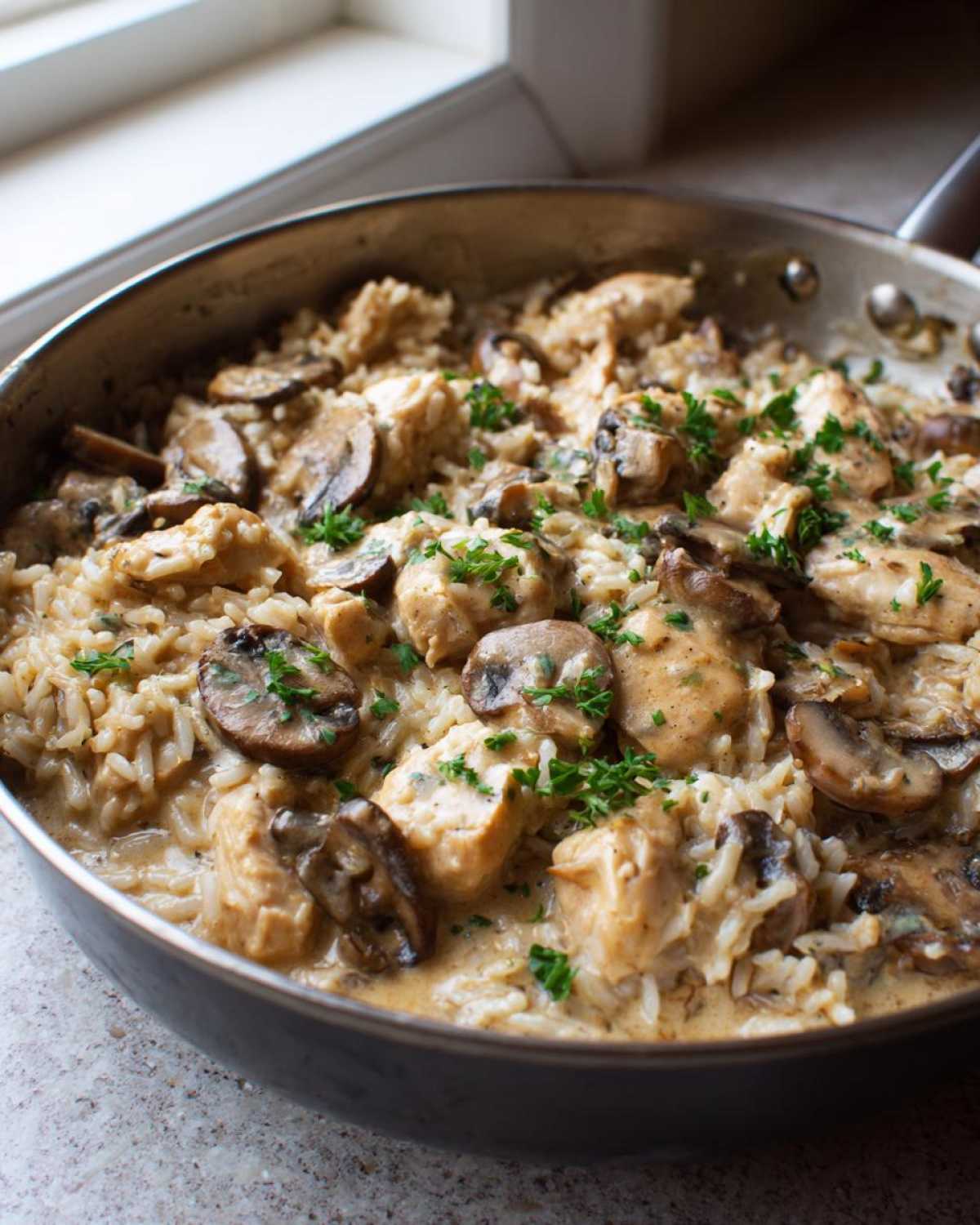 Close-up of a skillet filled with Creamy Mushroom Chicken and Rice Skillet, garnished with fresh parsley.