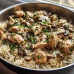 A close-up of Creamy Mushroom Chicken and Rice Skillet served directly in a metal skillet, topped with fresh parsley.