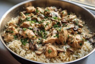 A close-up of Creamy Mushroom Chicken and Rice Skillet served directly in a metal skillet, topped with fresh parsley.