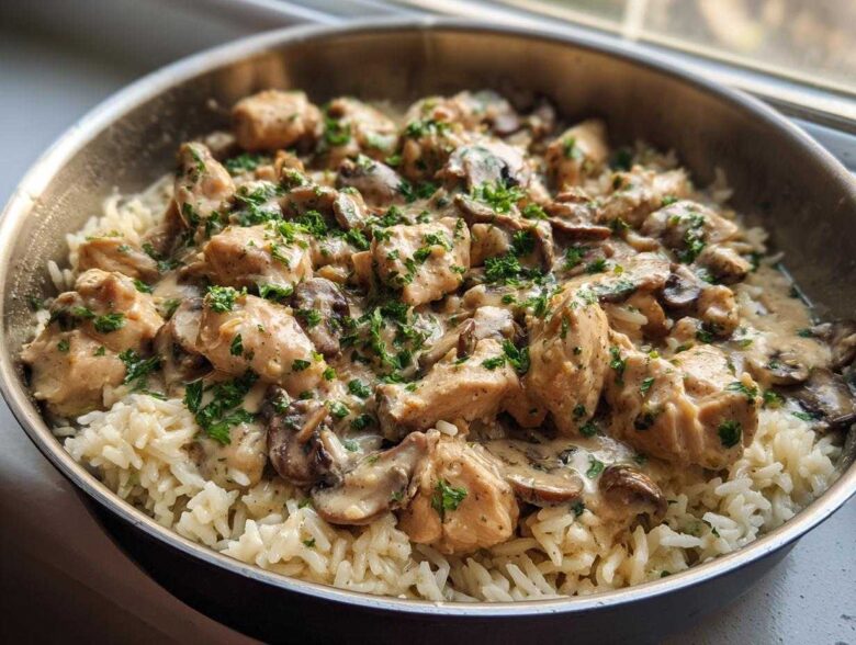 A close-up of Creamy Mushroom Chicken and Rice Skillet served directly in a metal skillet, topped with fresh parsley.