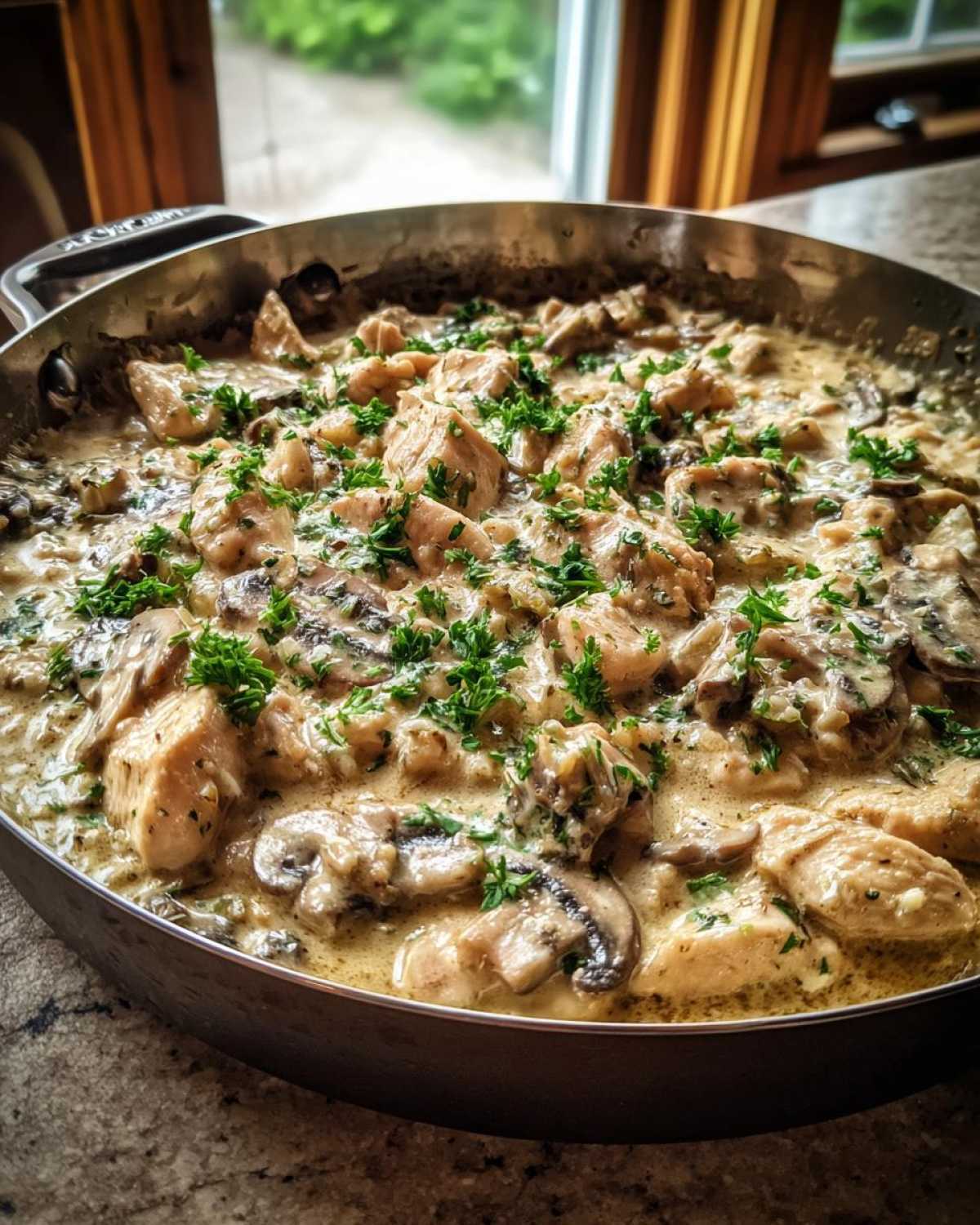 Close-up of Creamy Mushroom Chicken and Rice Skillet garnished with fresh parsley in a stainless steel pan.