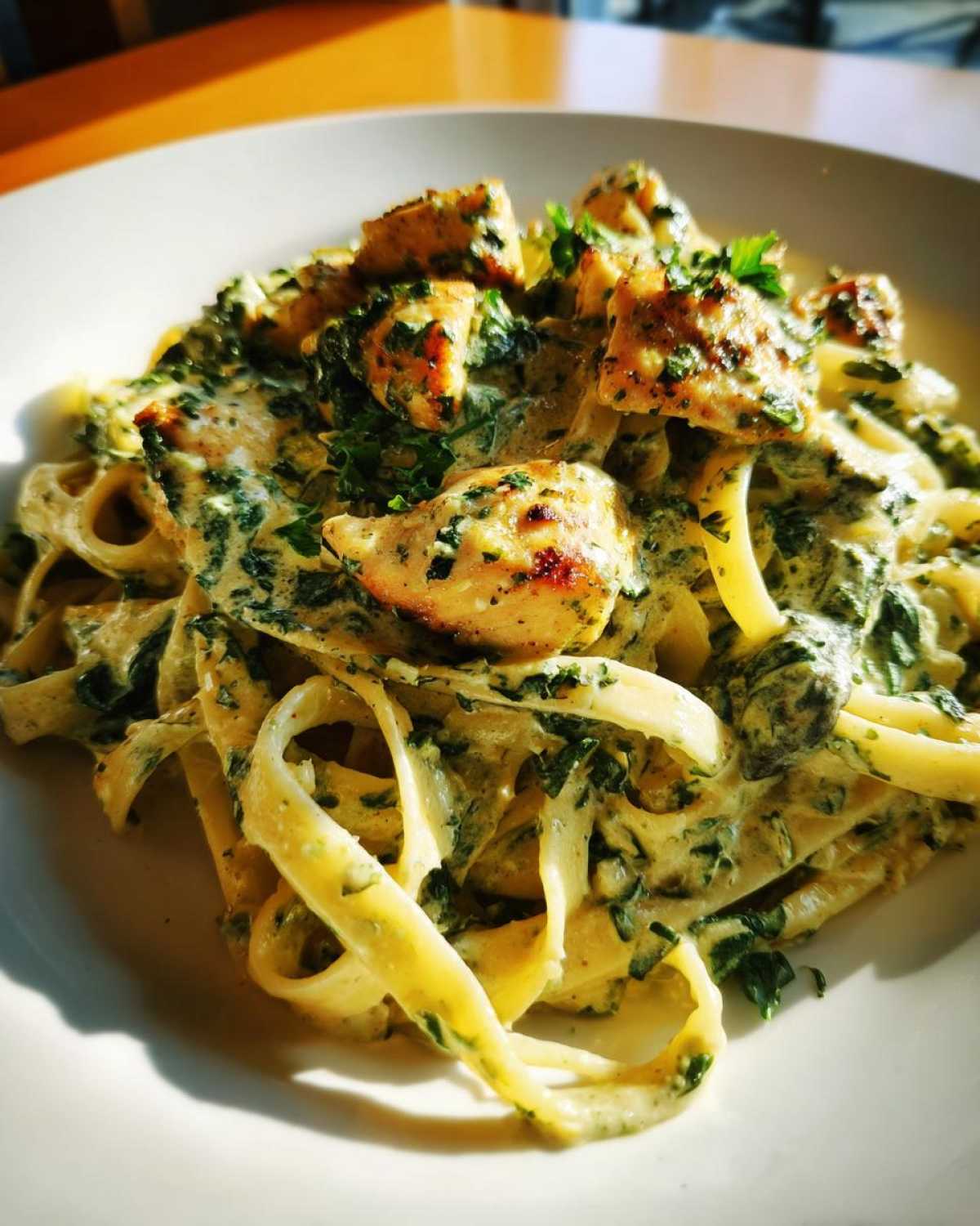 A close-up of fettuccine coated in creamy spinach sauce, topped with grilled chicken pieces, making a perfect Creamy Spinach Pasta with Chicken Dinner.