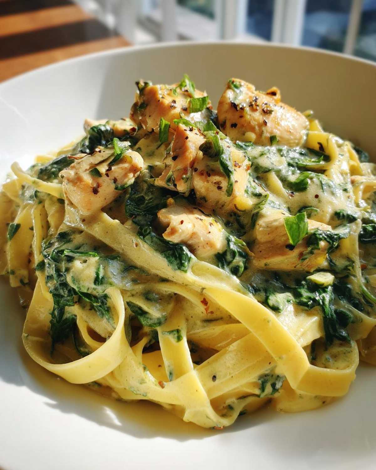 Close-up of fettuccine pasta tossed in a rich, creamy sauce with spinach and chunks of seasoned chicken, perfect for a Creamy Spinach Pasta with Chicken Dinner.