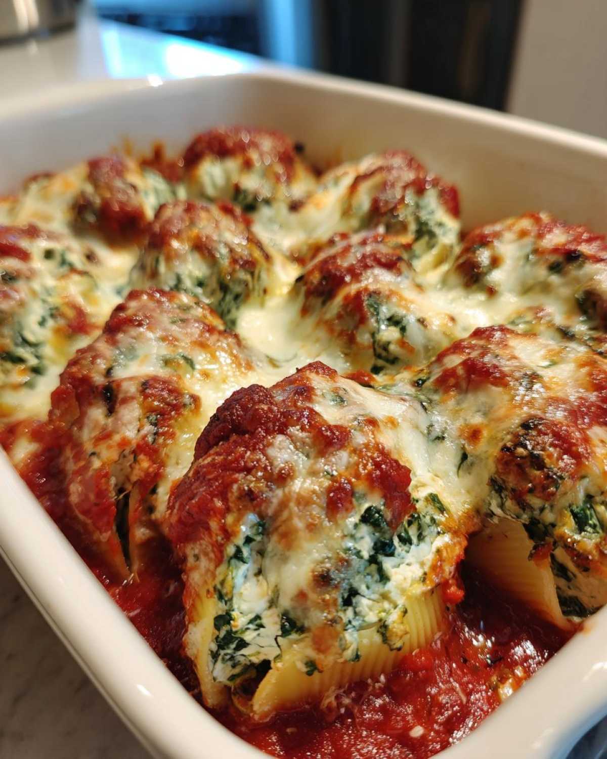 Close-up of baked Creamy Spinach and Ricotta Stuffed Shells covered in melted cheese and marinara sauce.