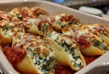 Close-up of baked Creamy Spinach and Ricotta Stuffed Shells topped with melted cheese and marinara sauce.