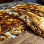 Close-up of crispy, golden-brown Cheesy Chicken Quesadilla slices oozing melted cheese and shredded chicken.