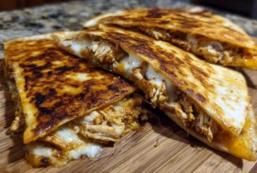 Close-up of crispy, golden-brown Cheesy Chicken Quesadilla slices oozing melted cheese and shredded chicken.