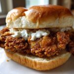 Close-up of a Crispy Chicken Burger with Garlic Mayo piled high on a soft bun, showing the crunchy texture.