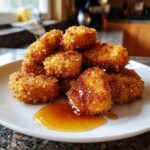 A pile of golden brown, perfectly Crispy Chicken Nuggets with Honey Dip drizzled on a white plate.