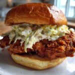 A perfectly assembled Crispy Chicken Sandwich with Creamy Slaw piled high on a brioche bun.