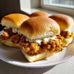 Four delicious Crispy Chicken Sliders with Garlic Sauce piled high on soft buns, served on a white plate.