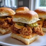 Four delicious Crispy Chicken Sliders with Spicy Mayo, pickles, and soft buns, arranged on a white plate.