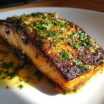 Close-up of a perfectly cooked Garlic Butter Salmon with Crispy Skin Recipe, topped with herbs.