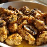 Close-up of tender pieces of Garlic Butter Chicken and Mushroom Skillet Dinner coated in a rich, herby garlic butter sauce.