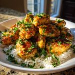 Close-up of golden Garlic Butter Chicken Bites generously topped with fresh parsley, served over a bed of white rice.