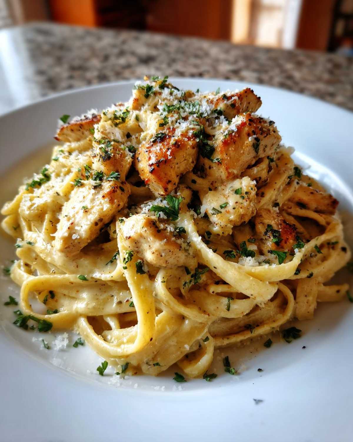 A close-up of creamy Garlic Butter Chicken Pasta with Parmesan, topped with grilled chicken pieces and fresh parsley.