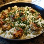 Close-up of Garlic Butter Rice with Chicken Skillet, featuring browned chicken pieces nestled in buttery rice and topped with fresh parsley.