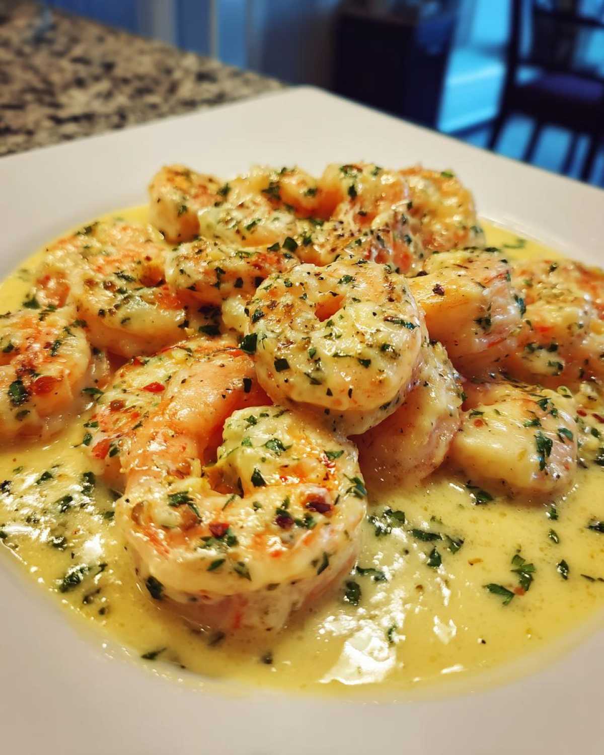 Close-up of cooked shrimp coated in a rich, creamy parmesan sauce, garnished with parsley.