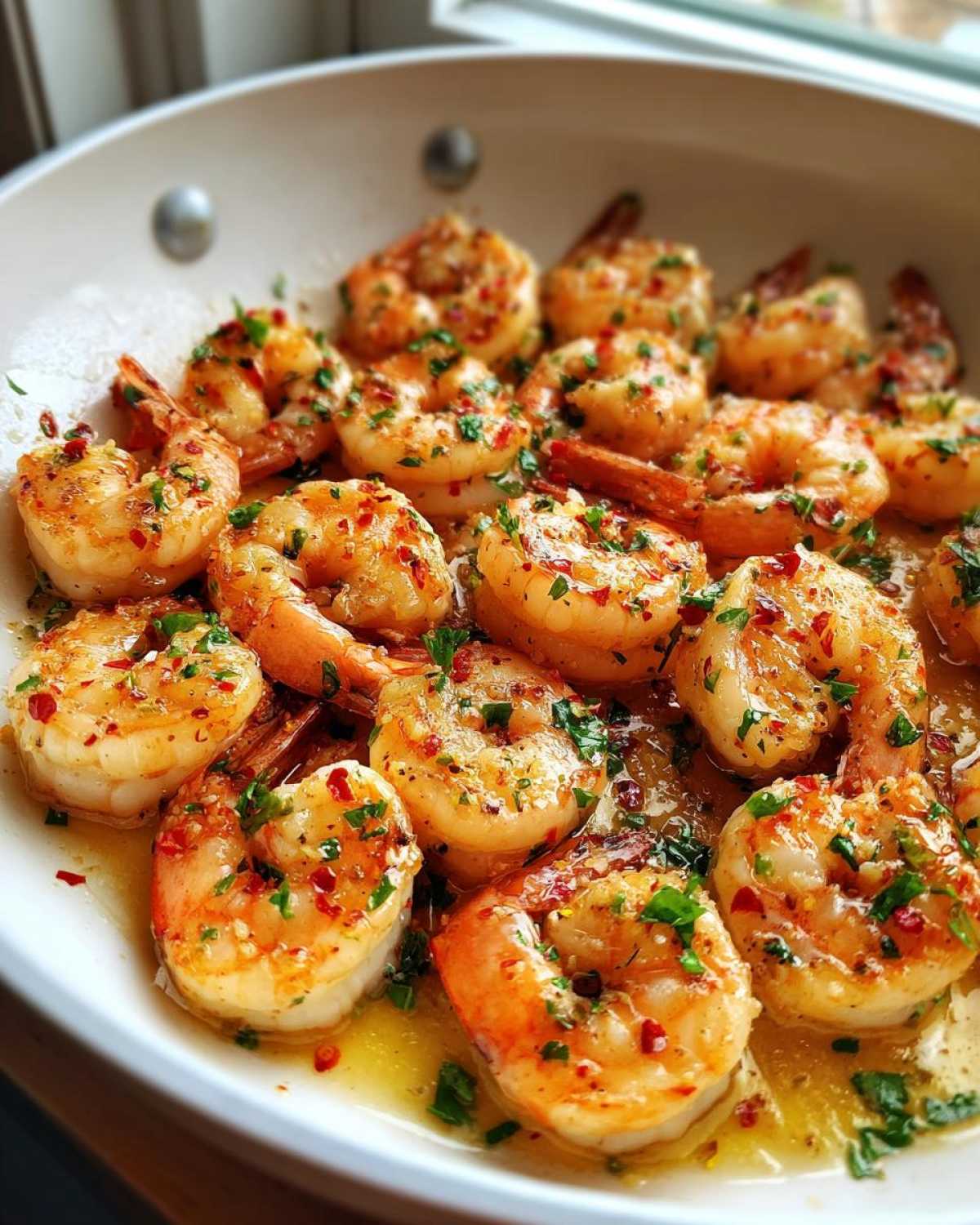 Close-up of plump shrimp cooked in a Garlic Butter Shrimp Skillet with Lemon Sauce, topped with parsley and red pepper flakes.