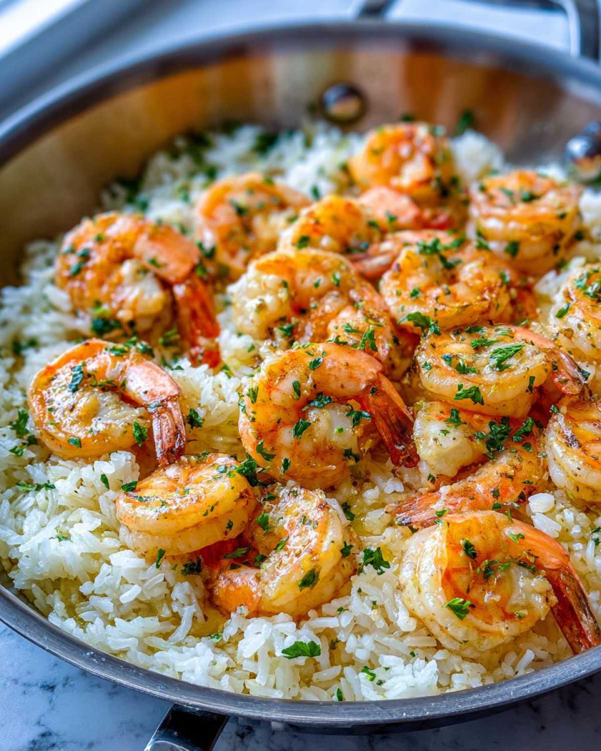 Close-up of juicy, orange Garlic Butter Shrimp with Rice Skillet, garnished with fresh parsley.