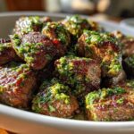 Close-up of juicy, seared Garlic Butter Steak Bites generously topped with a vibrant green herb sauce.