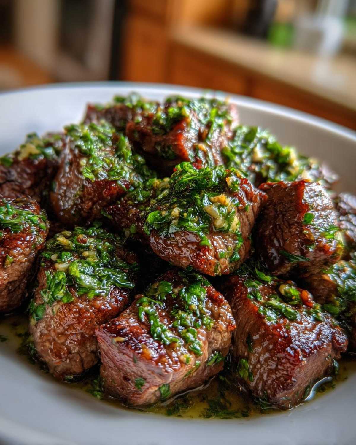 Close-up of seared Garlic Butter Steak Bites generously topped with a vibrant green herb sauce.
