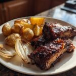 Close-up of Honey BBQ Chicken Bake pieces served with roasted potatoes and caramelized onions on a white plate.