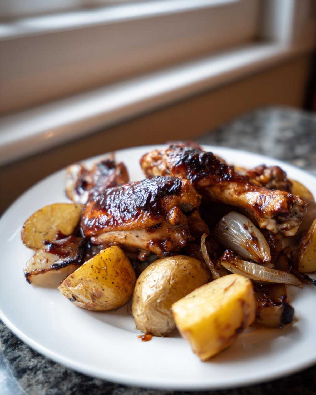 A plate featuring glazed chicken pieces and roasted potatoes, part of the Honey BBQ Chicken Bake with Potatoes recipe.