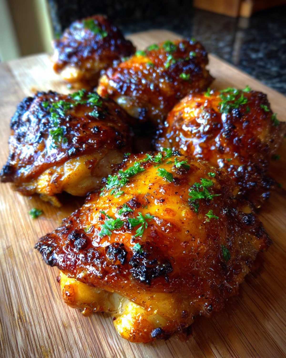 Close-up of several pieces of Honey Butter Chicken Skillet with a shiny, caramelized glaze and chopped parsley garnish.