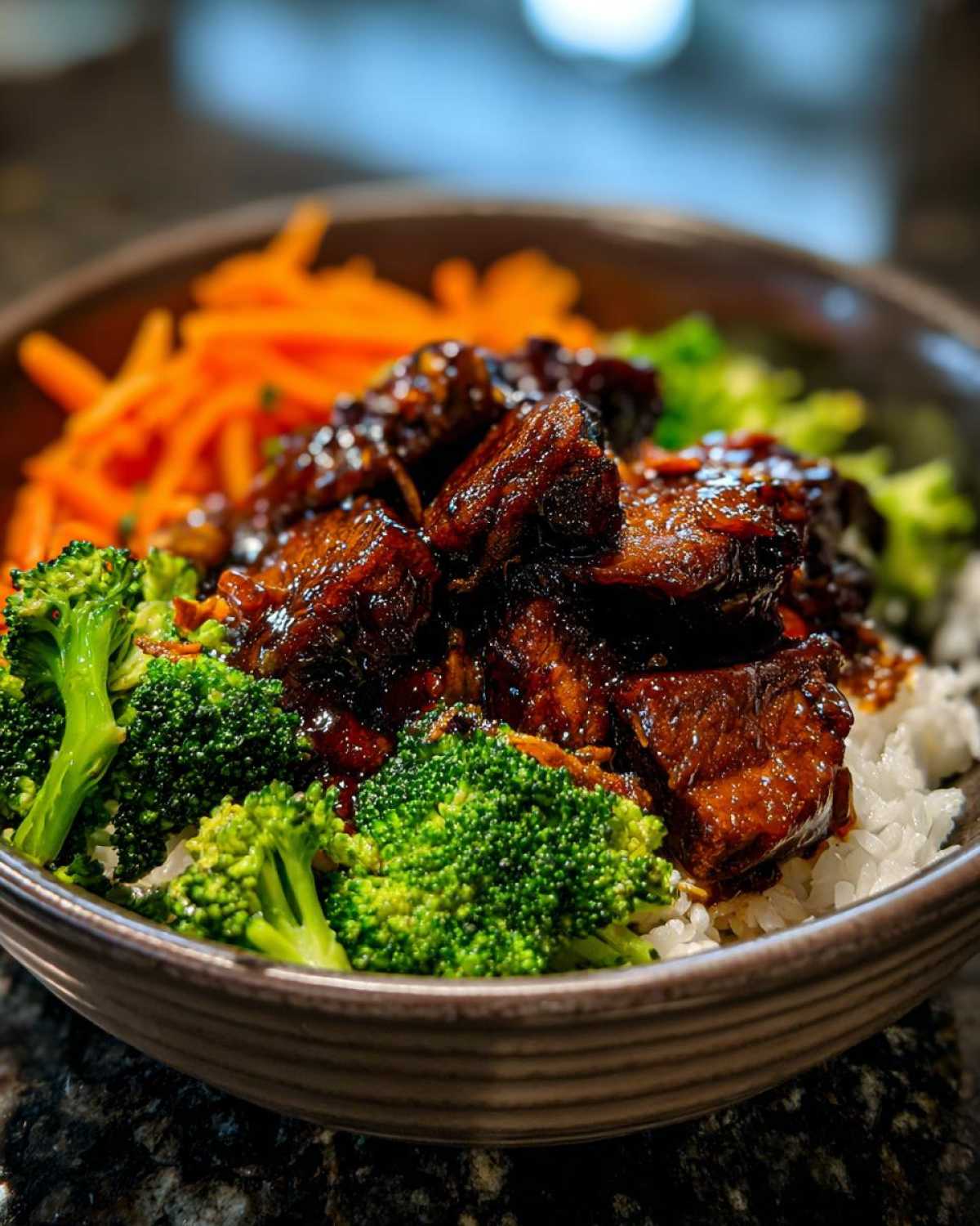 Close-up of a Honey Garlic Chicken Bowl featuring glazed chicken pieces, bright green broccoli florets, and shredded carrots over white rice.