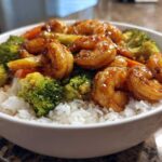 Close-up of a white bowl filled with white rice topped with glazed shrimp and bright green broccoli florets for a Honey Soy Shrimp Bowl.