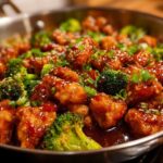 Close-up of Honey Sriracha Chicken Skillet pieces coated in glaze with bright green broccoli florets.