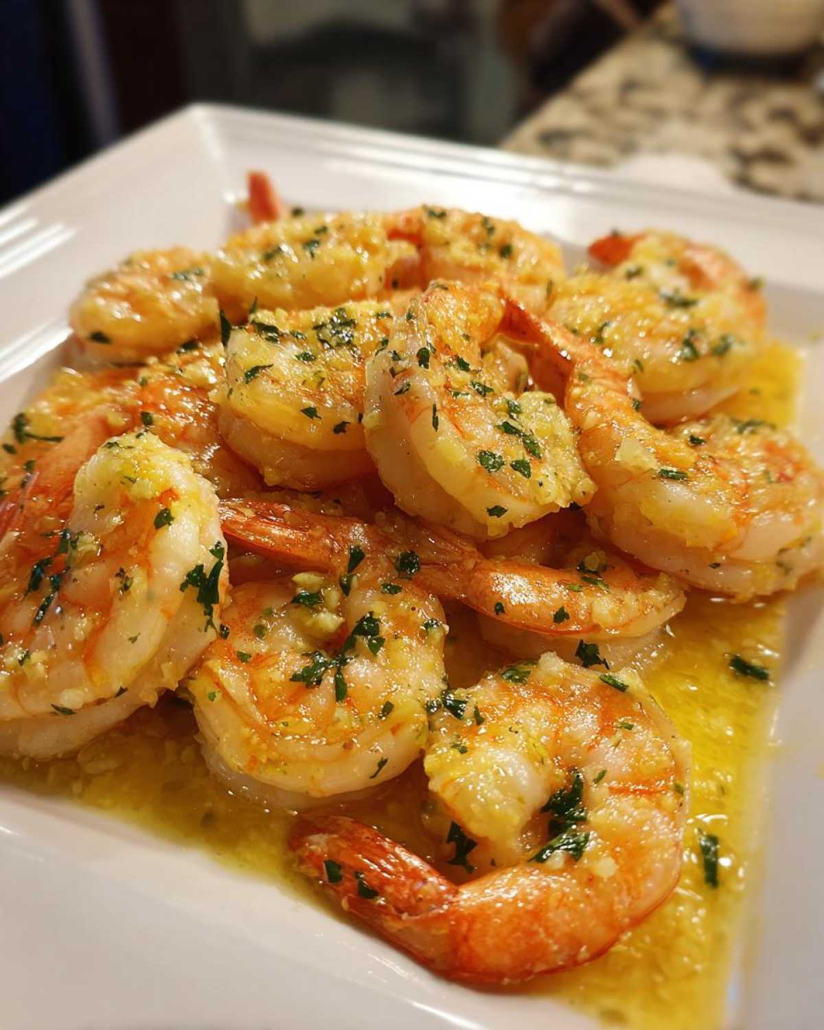 Close-up of cooked shrimp generously coated in a bright lemon butter sauce with visible minced garlic and parsley, showcasing the Lemon Butter Shrimp with Garlic Flavor.