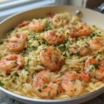 Close-up of a one-pan Lemon Garlic Shrimp Orzo Dinner topped with fresh parsley in a light-colored skillet.