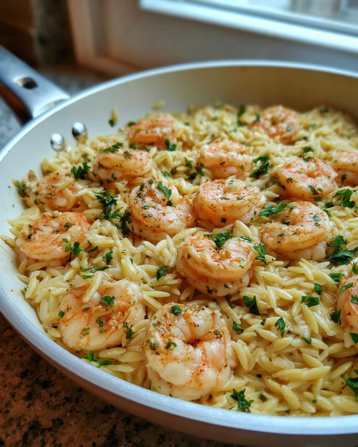 Close-up of Lemon Garlic Shrimp Orzo One Pan Dinner topped with fresh parsley in a white skillet.