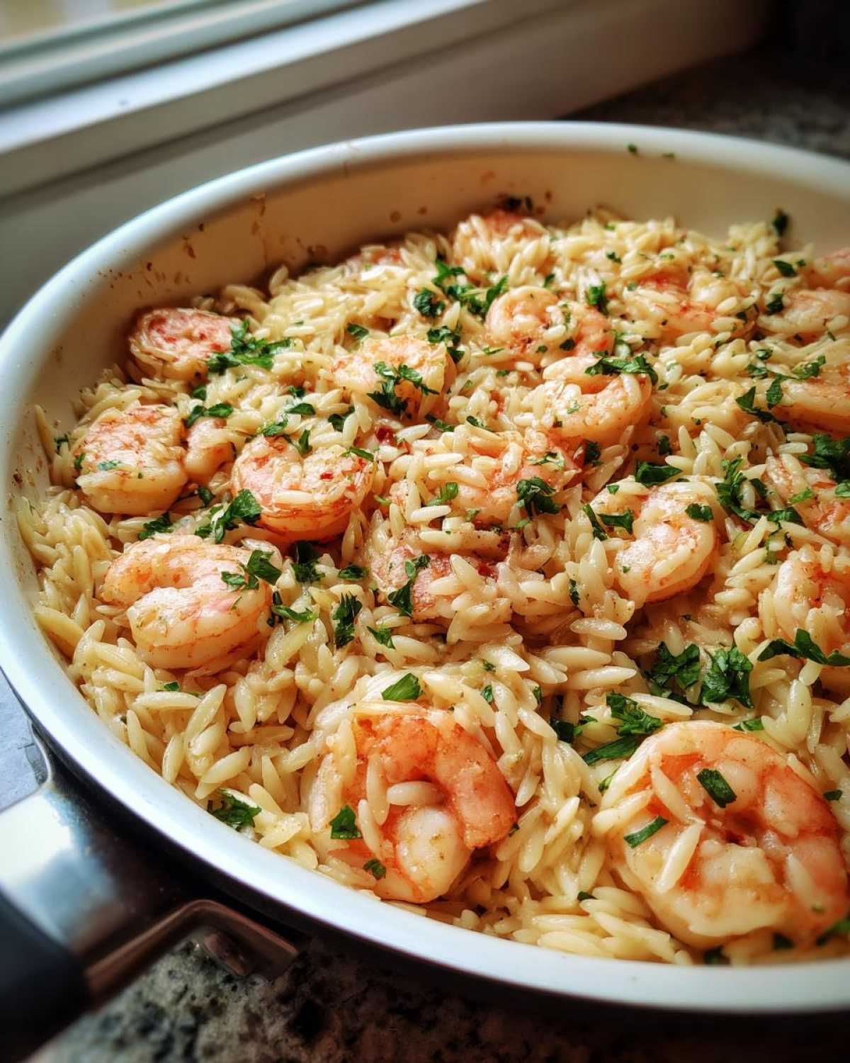 Close-up of a one-pan Lemon Garlic Shrimp Orzo Dinner garnished with fresh parsley in a white skillet.