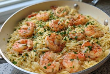Close-up of a one-pan Lemon Garlic Shrimp Orzo Dinner topped with fresh parsley in a light-colored skillet.