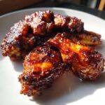 Close-up of perfectly cooked Sticky BBQ Chicken Wings Crispy Oven Style glistening with sauce on a white plate.