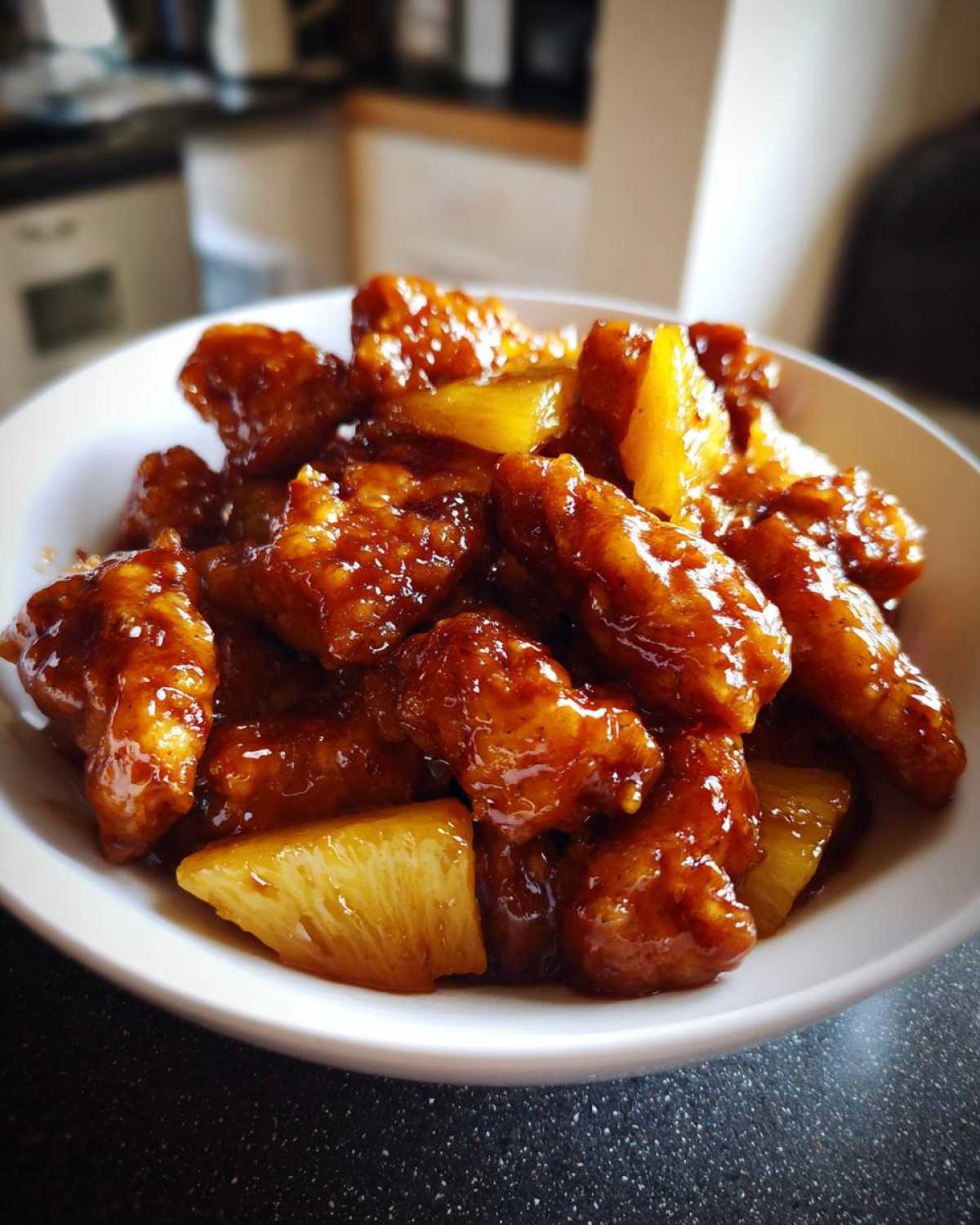 Close-up of Sticky Pineapple Chicken with Sweet Glaze pieces coated in a rich, dark sauce, mixed with chunks of pineapple.