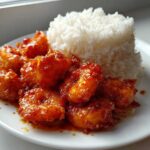 Plate of Sticky Sweet Chili Shrimp coated in glossy sauce next to a mound of fluffy white rice.