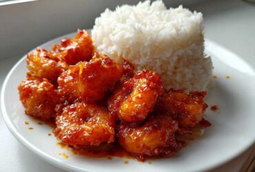 Plate of Sticky Sweet Chili Shrimp coated in glossy sauce next to a mound of fluffy white rice.