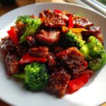 Close-up of glistening, saucy pieces of Sticky Teriyaki Chicken Stir Fry Quick Meal mixed with bright green broccoli florets and red bell peppers.