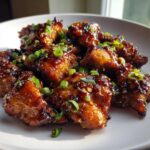 Close-up of glazed Sticky Teriyaki Chicken Thighs with Garlic, topped with sesame seeds and green onions.