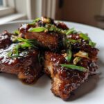 Close-up of glistening Sticky Teriyaki Chicken Thighs with Garlic, garnished with sliced green onions.