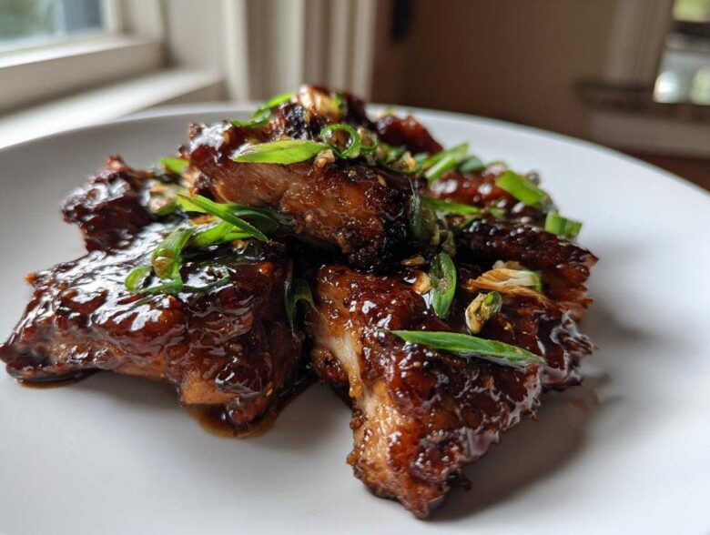 Close-up of glistening Sticky Teriyaki Chicken Thighs with Garlic, garnished with sliced green onions.