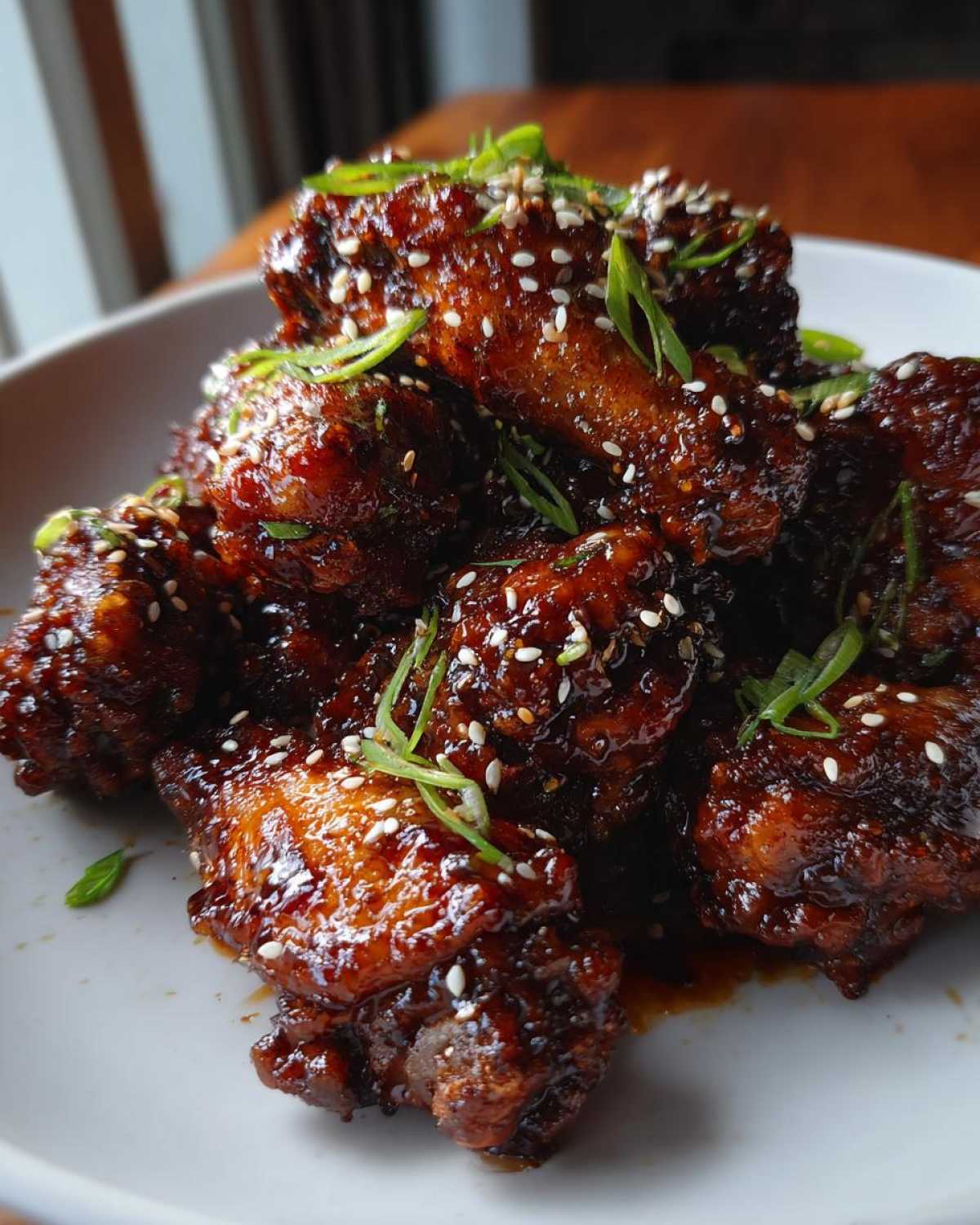 A close-up of glistening Sticky Teriyaki Chicken Wings Oven Baked, garnished with sesame seeds and sliced green onions.