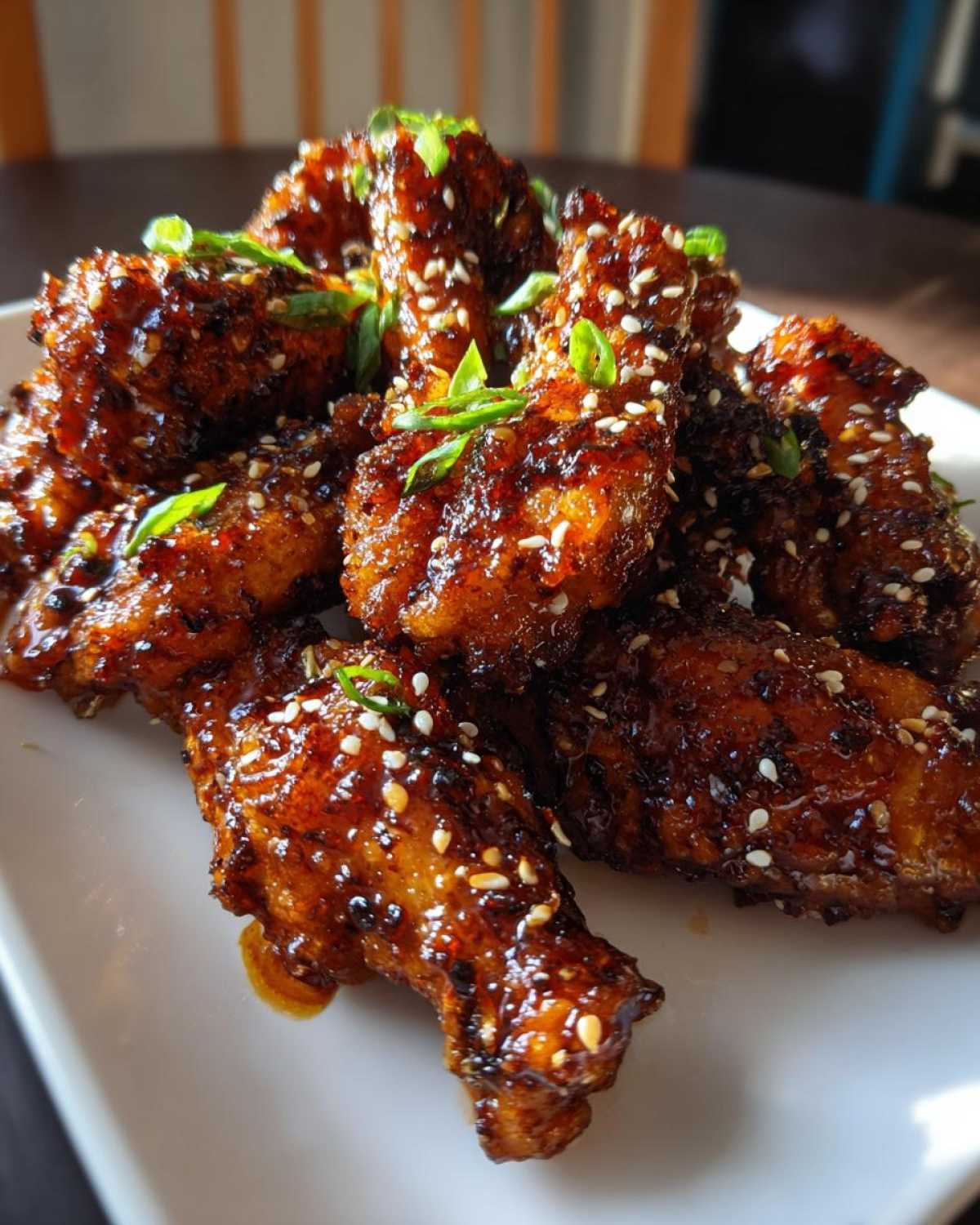 Close-up of glossy, glazed Sticky Teriyaki Chicken Wings Oven Baked, sprinkled with sesame seeds and green onions.