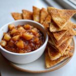 A bowl of chunky Apple Pie Salsa next to a stack of cinnamon sugar chips.
